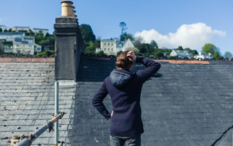 Woman Doing a Roof Inspection From Outside To See If The Roof Needs A Replacement